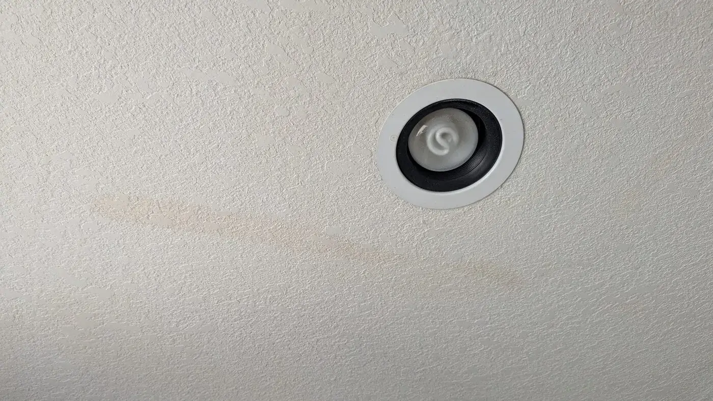 Water stain on a ceiling next to a recessed light
