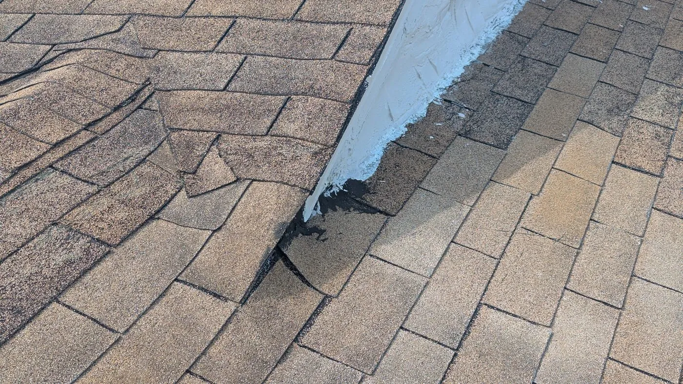 Lifted and damaged shingles along roof flashing
