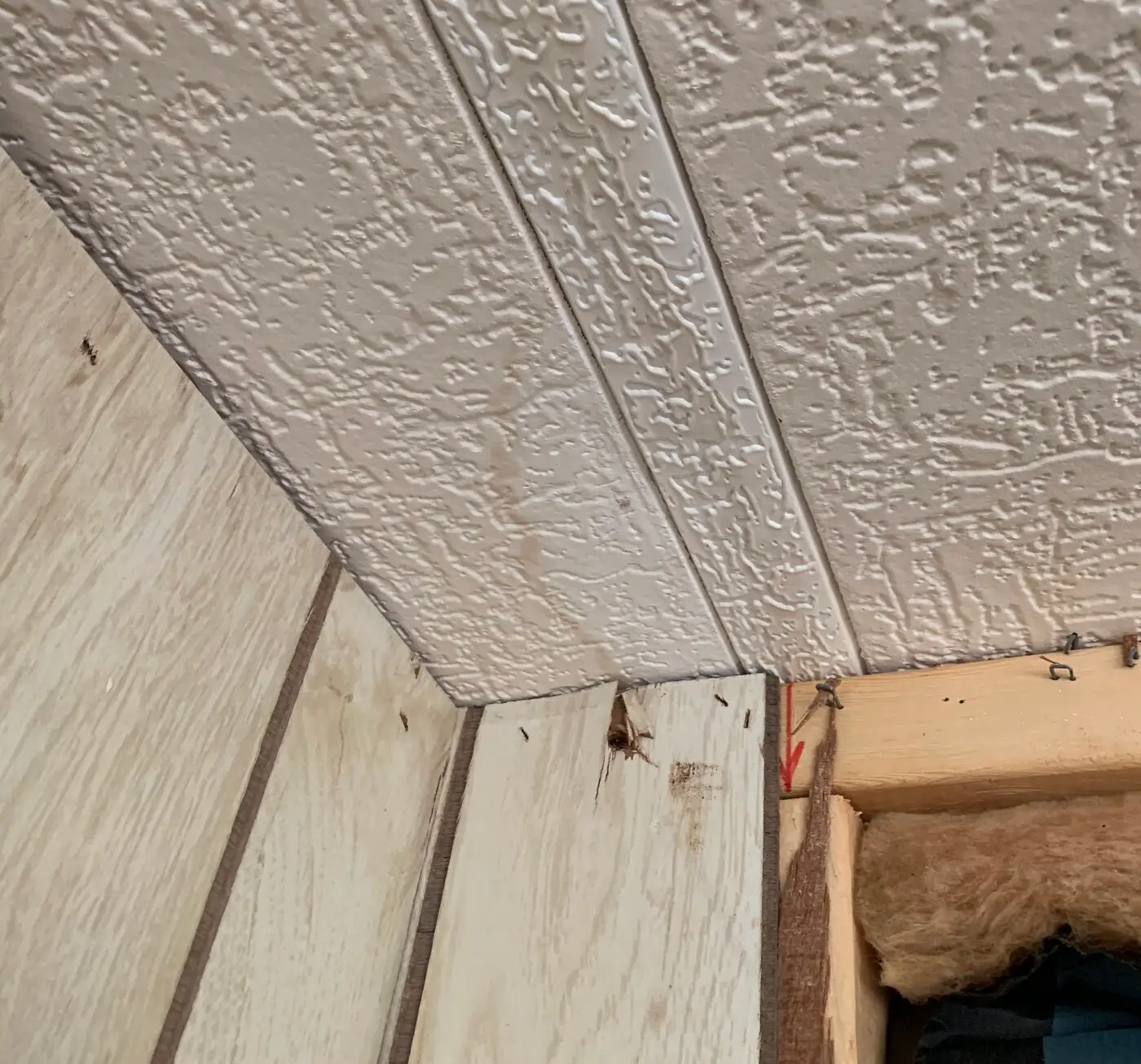 Water-damaged wall and ceiling corner with exposed insulation