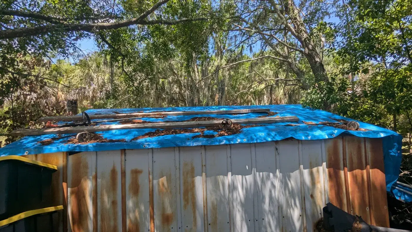 Storm-damaged structure covered with a blue tarp